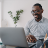 Man smiling at screen because the Virgin Islands Department of Immigration Launches New Online Application